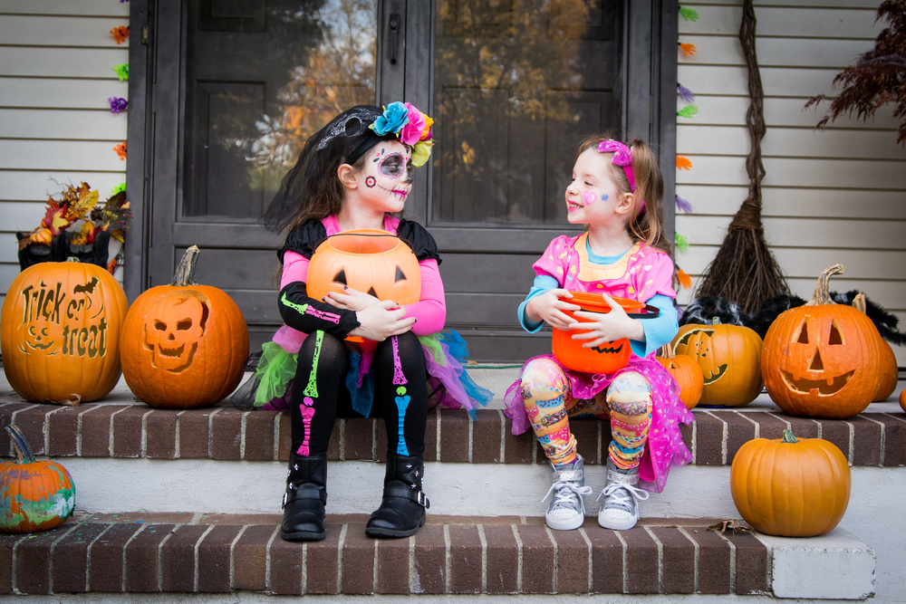 Halloween sisters sitting on porch trick or treating